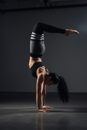 Person wearing gray leggings with black and white stripes and a black sports bra on a light background