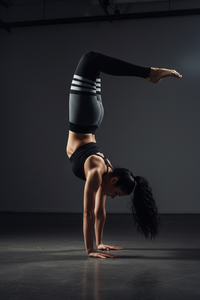 Person wearing gray leggings with black and white stripes and a black sports bra on a light background